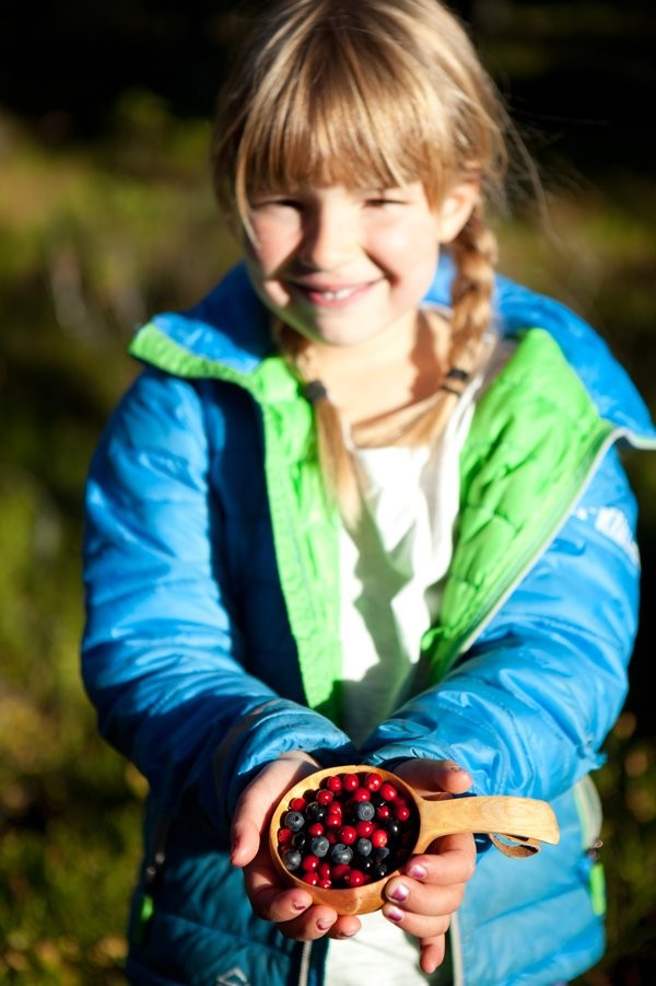 Mädchen hält eine Holztasse mit Beeren in den Händen